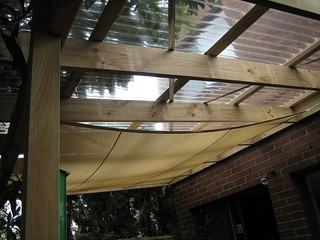 Pérgola com estrutura em madeira, policarbonato e cortina. Assim fica mais fácil controlar a luz. Foto de babbagecabbage