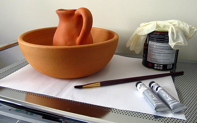 Separe o material necessário para impermeabilização e forre sua mesa de trabalho com papel. Não esqueça de lavar bem os vasos antes para remover qualquer poeira que possa prejudicar a pintura. Neste tutorial usaremos uma bacia e um jarro de cerâmica.